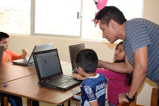 A teacher instructing a student on a donated laptop.