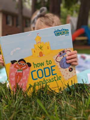 Young girl reading How to Code a Sandcastle Young girl reading How to Code a Sandcastle